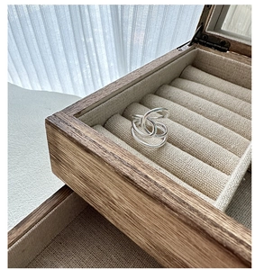 Nahaufnahme eines S925 Silberringes mit Knotendesign und mehreren Lagen auf Holzbox