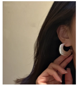 Detail of large S925 silver acetate C-shaped hoop earrings with iridescent pearl finish