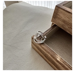 Nahaufnahme eines S925 Sterlingsilber Knotrings auf einer hölzernen Schmuckschatulle