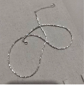 Détail d'un collier en argent S925 avec fermoir mousqueton et petit pendentif cœur