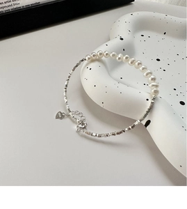 Detail of S925 silver beaded necklace with freshwater pearls and a heart-shaped charm