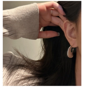Detail view of modern S925 sterling silver hoop earrings with high polish metallic finish