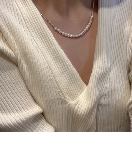 Detail of S925 sterling silver pearl necklace worn on neck with elegant knit sweater