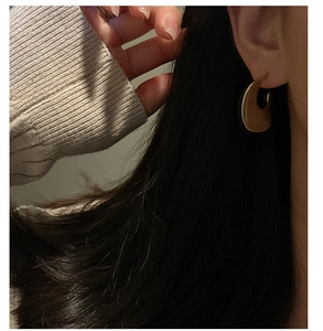 Detail of matte gold crescent earring on model with elegant minimalist style