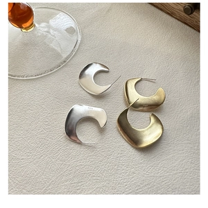 Macro detail of S925 sterling silver stamp on matte gold and polished silver hoop earrings