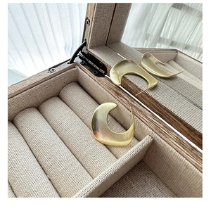 Detail view of gold matte finished C-shaped sterling silver hoop earrings in a jewelry box