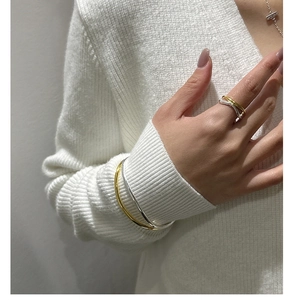 Detailed close-up of mixed metal silver and gold wave ring worn with simple bangles