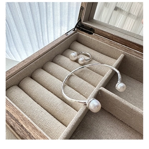 Detailed view of silver pearl jewelry set in a luxury wooden box with natural lighting