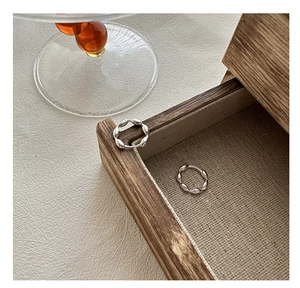 Macro shot of silver twisted link earrings with polished finish on a wooden tray