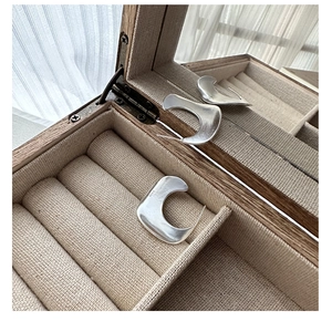 Close-up of S925 sterling silver matte C-shaped earrings in a wooden jewelry box