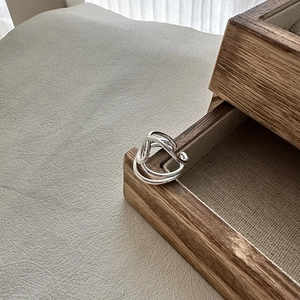 Minimalistischer S925 Sterlingsilber Knotenring auf einer hölzernen Schmuckschatulle