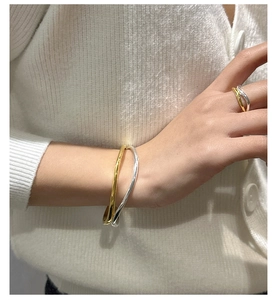Close-up of dual-tone silver and gold wavy rings and bracelet on a model's hand
