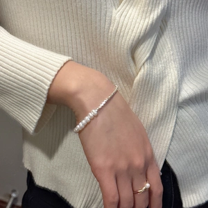 Detailed view of S925 silver pearl bracelet and matching ring on a soft knit sweater