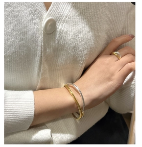 Detail of minimalist silver and gold wave ring with sleek metallic finish on hand