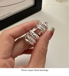 Gros plan détaillé de boucles d'oreilles torsadées triple couche texture argentée