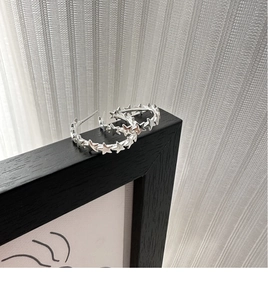 Close-up of S925 sterling silver C-shaped hoop earrings with interlocking star pattern