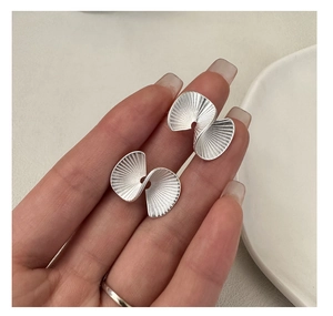 Macro shot of silver fan-shaped stud earrings with fine vertical ribbed textures