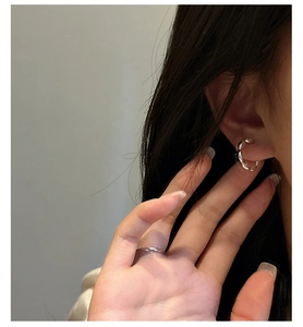 Close-up of stylish S925 sterling silver twisted hoop earrings and minimalist band ring