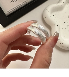 Detail of C-shaped S925 sterling silver earrings with a brushed sparkling texture