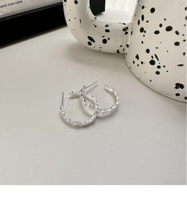 Detailed close-up of S925 sterling silver C-shaped hoop earrings with star textures
