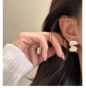 Macro detail of S925 sterling silver fan earrings with matte textured wavy folds