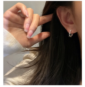 Close-up of minimalist S925 sterling silver hoop earrings with a twisted metal texture