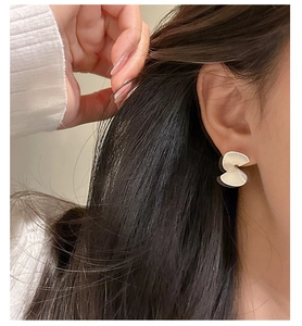 Close-up of a model wearing S925 sterling silver fan-shaped earrings with matte radial texture