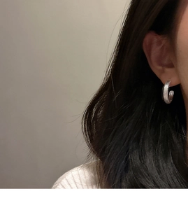 Close-up of S925 sterling silver C-shaped earrings with brushed glitter texture on model
