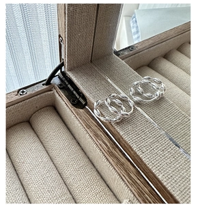 Macro detail of S925 sterling silver twisted hoop earrings in a wooden jewelry box