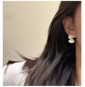 Macro detail of S925 sterling silver fan-shaped earring with matte brushed texture