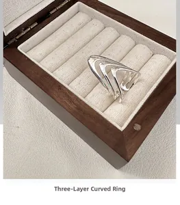 Macro shot of silver triple-layered curved ring displayed in a premium wooden jewelry box