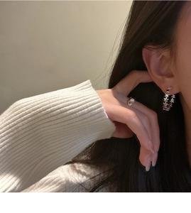 Detail of S925 sterling silver star-shaped earrings and minimalist gold pearl ring on model