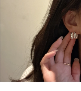 Gros plan de boucles d'oreilles créoles torsadées triple couche en argent S925 sur un mannequin