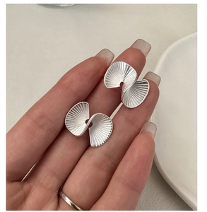 Macro detail of matte S925 sterling silver fan-shaped earrings with radial texture