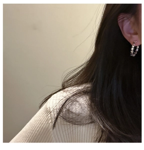 Detailed side view of a model wearing S925 sterling silver hoop earrings with star motifs