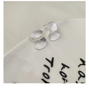 Detailed macro view of S925 sterling silver fan-shaped stud earrings on a white plate