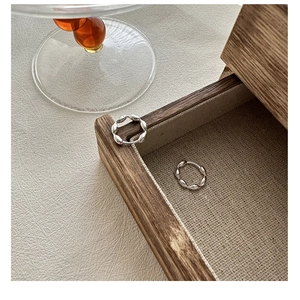Close-up of S925 sterling silver hoop earrings with twisted croissant texture on wood