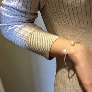 Elegant S925 sterling silver open bangle featuring two large white pearls on a knit background