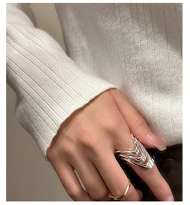Close-up of a multi-layered V-shaped silver ring on finger with white knit sweater