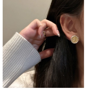Close-up of dual-tone S925 silver stud earrings with vintage gold portrait relief detail