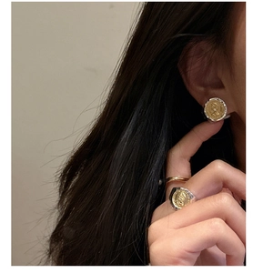 Close-up of S925 silver and gold coin-style portrait earrings and ring set on a model