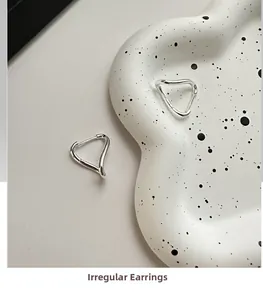 Macro detail of irregular twisted 925 sterling silver hoop earrings on a marble tray