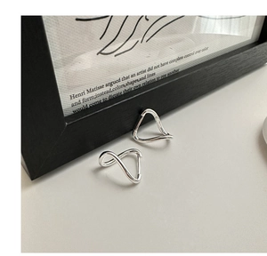 Macro shot of silver wave earrings with twisted design on minimalist stone surface