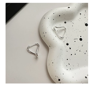 Detailed view of polished 925 sterling silver wavy triangle hoop earrings on a tray