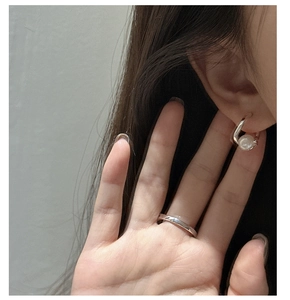 Gros plan de boucles d'oreilles perles en argent S925 et bague minimaliste sur un modèle