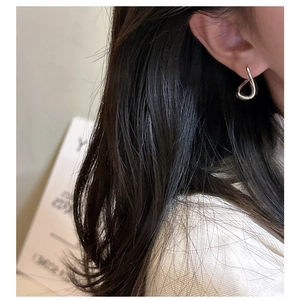 Close-up of 925 sterling silver twisted knot earring on a model for a minimalist style