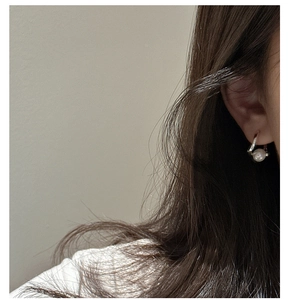 Gros plan d'une boucle d'oreille en argent S925 avec perle portée par un mannequin élégant