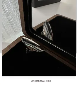 Macro view of minimalist silver curved ring in a wooden jewelry box with mirror reflection