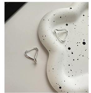 Macro detail of geometric wave sterling silver hoop earrings on a ceramic dish