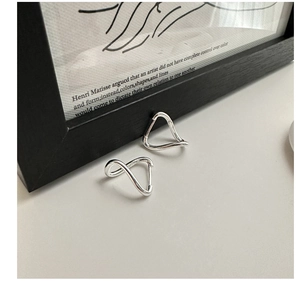 Macro shot of 925 sterling silver twisted wave earrings on a minimalist grey surface
